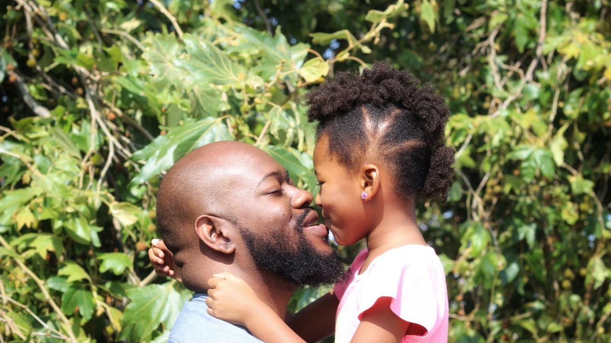 Père et fille complices souriants en extérieur